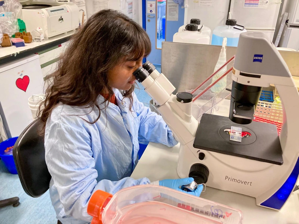Picture of Aruna Sreenivasan looking through a microscope