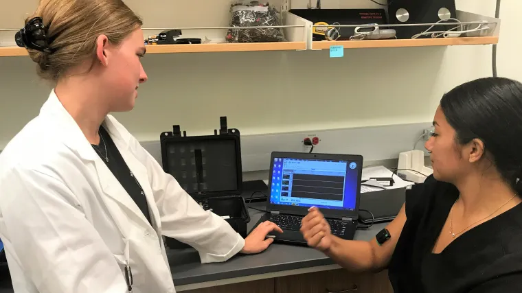 Picture of Paige Rudy explaining tasks and data collection to a fellow student in front of a computer