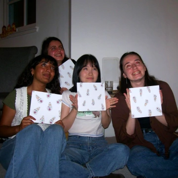 Picture of Aruna and her labmates, holding up samples of artwork